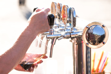 close-up of barman hand at beer tap pouring a draught lager beer