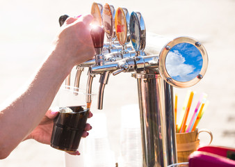 close-up of barman hand at beer tap pouring a draught lager beer