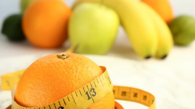 Fresh citrus fruits. Rotation Video footage of the concept of healthy eating and diet. A spinning ripe orange wrapped in a centimeter, with a background of fruit banana, lemon, lime, orange, apples