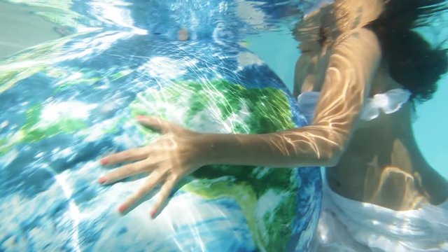 Woman underwater kisses inflated globe, close up