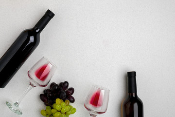 Glasses and bottles of red and white wine on white background from top view