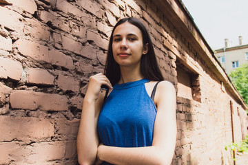 A very beautiful and cheerful girl stands on the street near a brick wall