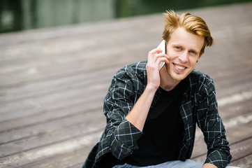 Fototapeta premium Tall handsome happy young man speaking on the phone