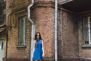 Fototapeta na wymiar A very beautiful and cheerful girl stands on the street near a brick wall