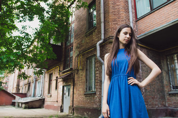 A very beautiful and cheerful girl stands on the street near a brick wall