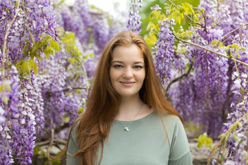 Natural beauty: red hair girl and freckles glow skin on the purple flowers background