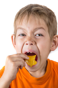 The boy is hungrily eating chips
