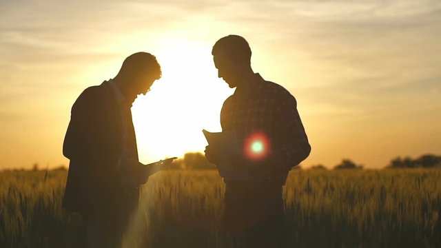 businessman holding tablet pc stand with farmer holding papers slow motion