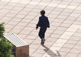 The boy runs along the pavement