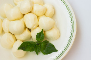 Mozzarella and green basil on a plate. White background, top view.
