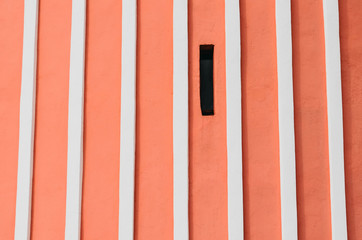 Red wall with vertical relief white stripes and narrow window.