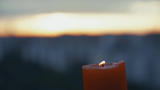 Candle light bickers in right corner behind blurred view of sunset.
