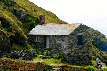 An isolated old stone house in the Scottish hills. An isolated old wooden chair in the house garden.
