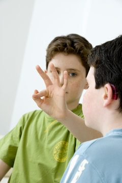 Models Do not use for HIV Young boy using the French sign language to discuss with his hearing-impaired brother The French sign language uses signs to designate words but also dactylology (each letter of the alphabet is represented by a defined position of the fingers then enabling to spell a word) and the lip reading The young boy designates the letter \f\ (see image nﾰ0833202 ans series of images from nﾰ0572308 to 0574108 to see the other letters of the alphabet)