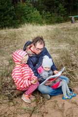 Father reads the book to his daughter in nature. Parental love.