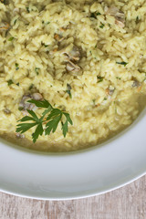 A white plate of risotto with clams, cockles and turmeric.