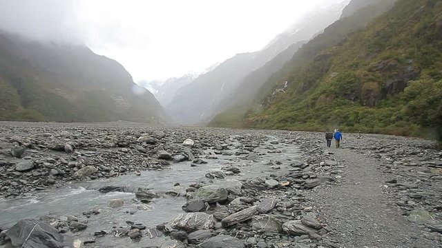tourist walking in franz josef glacier trail new zealand