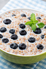 Buckwheat porridge in a bowl with mint leaves and blueberries.