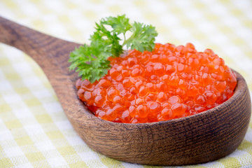 Salmon caviar with spoon on gray background.