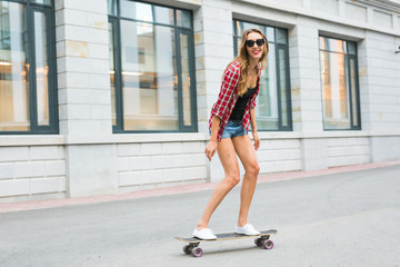 Young woman riding on her skateboard. Female skater practicing skating on the city.