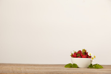 strawberries in a white bowl on a wooden table