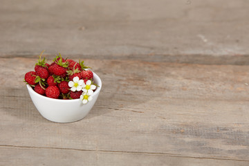 strawberries in a white bowl on a wooden table
