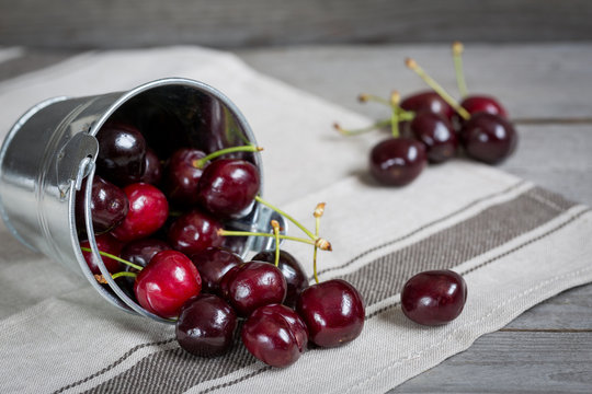 Ripe cherries and bucket on old wooden table