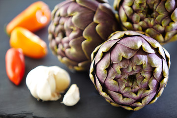 three artichokes with garlic bulb and chilis