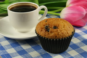 Chocolate muffins with a Cup of coffee and flowers on the table