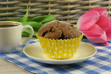 Chocolate muffins with a Cup of coffee and flowers on the table