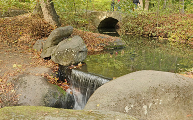 Meandering stream and waterfall surrounded by boulders in Arboretum Sofiyivka, Uman City, Ukraine, in autumn