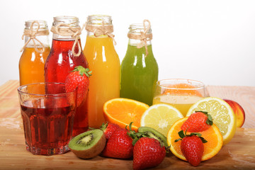 bottles of juice with kiwi with strawberries with lemon and orange