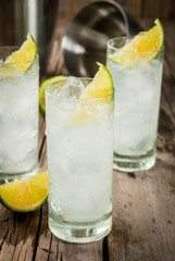 Alcoholic drink. Vodka and tonic highball cocktail with a lime garnish, on an old wooden rustic table. Copy space