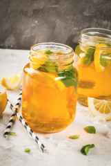 Chilled summer tea with ice, mint and lemon. Two portions in Mason Jars on a white stone table. Copy space