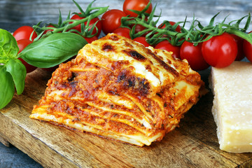 Serving of spicy traditional Italian beef lasagne in a restaurant - bolognese sauce topped with basil leafs
