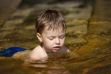 the child to learn to swim in the lake in summer day