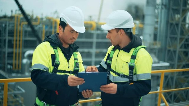 Two oil and gas workers duscussing at refinery industry.