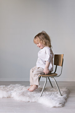 kleines Kind spielt zuhause mit einem Stuhl