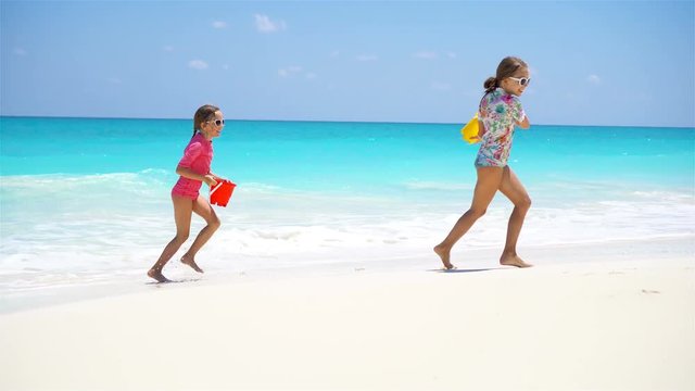 Adorable little girls have fun together on white tropical beach