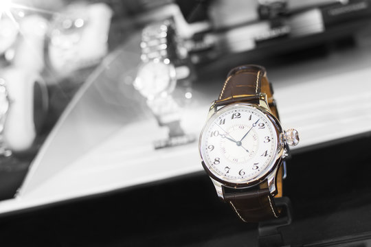 Beautiful brown leather watch in front of other watches. Focus on the watch. Black and white with color effect.