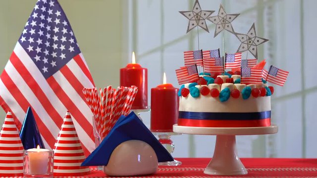 4k Fourth of July celebration party table with showstopper cake decorated with candy, stars and flag, placing cake and setting the table.