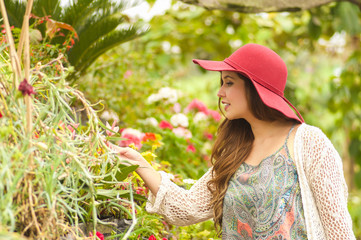 Cheerful young woman standing outdoors in garden wearing a red hat in garden background