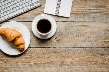 coffee and croissant for breakfast of businessman wooden office desk background top view space for text