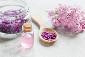 Obraz na płótnie Canvas lilac cosmetics with flowers and spa set on stone table background
