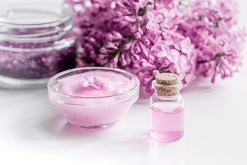 Obraz na płótnie Canvas lilac cosmetics with flowers and spa set on white table background
