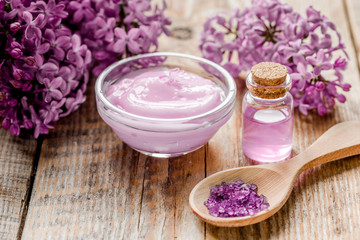 Obraz na płótnie Canvas take bath with lilac cosmetic set and blossom on wooden table background
