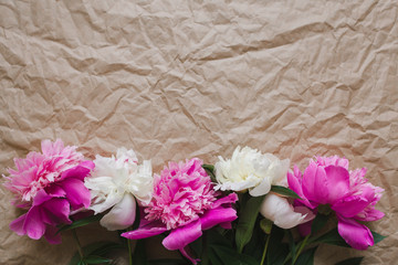 Delicate flowers on the photo of the craft paper. White and pink peonies lie on the table