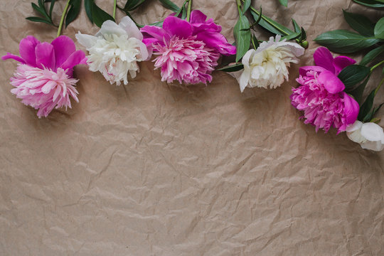 Delicate flowers on the photo of the craft paper. White and pink peonies lie on the table