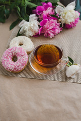 Fototapeta na wymiar Gentle breakfast. A cup of tea, flowers and donuts are on the table