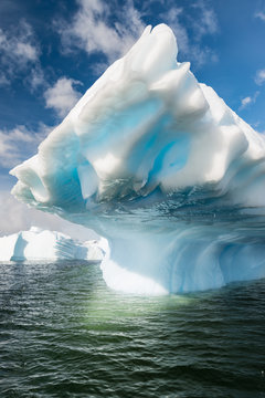 Azure shimmering beautiful iceberg in Antarctica with green reflection. 